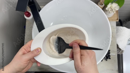 Hairdresser colorist mixes paint for hair dyeing bleaching.