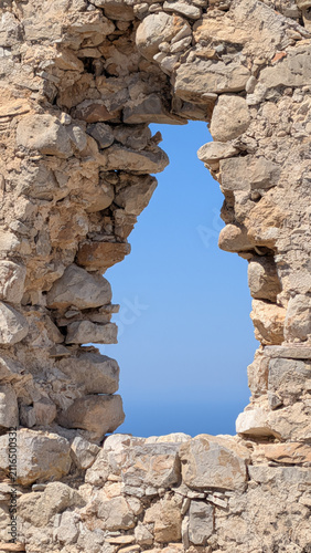 Obraz na płótnie Ouverture dans un mur de pierre antique avec vue sur le ciel bleu, Rhodes, Grèce