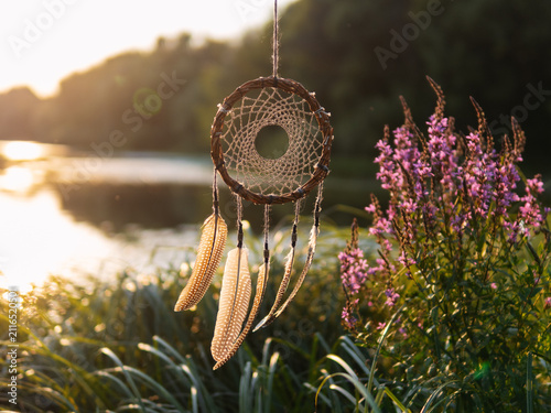 dreamcatcher made of willow on the background of the river at sunset