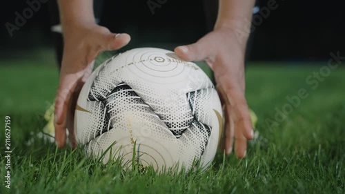 A footballer's hands place the ball on the turf of a football field before a shot