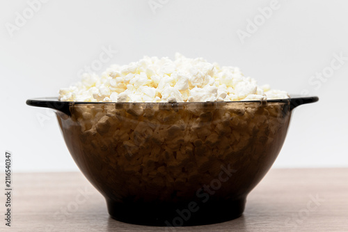 White crumbly cottage cheese in a deep black glass plate.