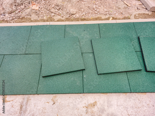 Foto Green rubber playground tiles being installed on a concrete surface
