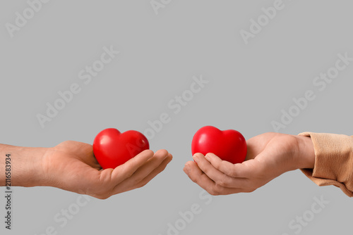 Two hands holding red heart...