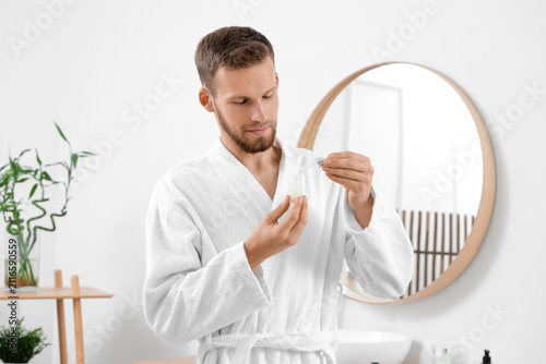 Young man applying serum to...