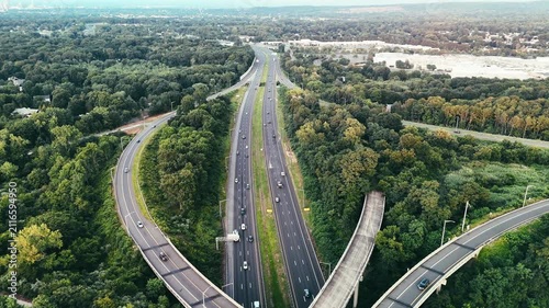 Aerial view of Connecticut highway interchange with traffic through green forest, representing transportation infrastructure, commuting, mobility, and regional connectivity. 4K.