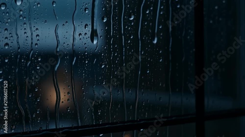 Raindrops on a windowpane amidst twilight gloom with subtle city lights
