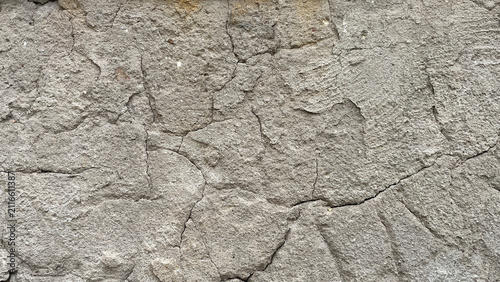 Фотография Close‑up of a weathered stucco wall with interconnected cracks and rough plaster texture, creating an abstract architectural background with signs of aging and surface deterioration
