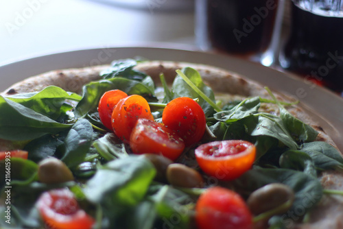 Foto Plate of vegetarian pizza with pesto, tomatoes, basil and olives