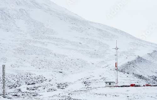 Mobile communications building and communication tower standing on an arctic snowy mountain slope Iceland blizzard weather