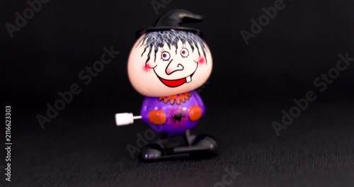 Playing with a cute mechanical wind-up Halloween character on a dark background. Halloween and preparations for it