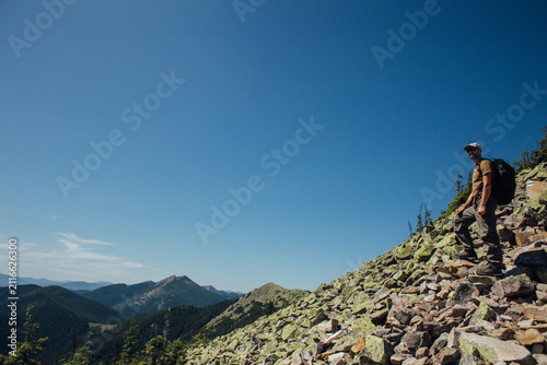 Tourist with a backpack in the mountains watching a beautiful view
