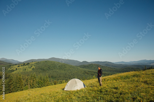 Tourist watching the mountain landscape near the tent