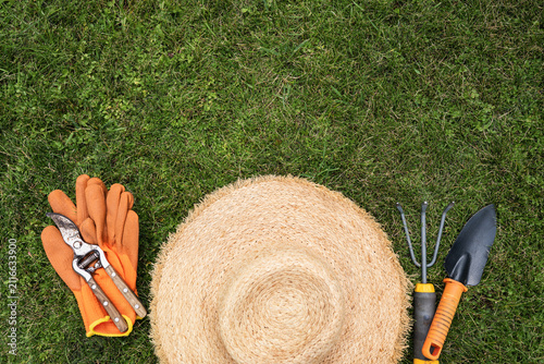 Obraz na plátně Gardening gloves straw hat and pruning shears on green grass top view