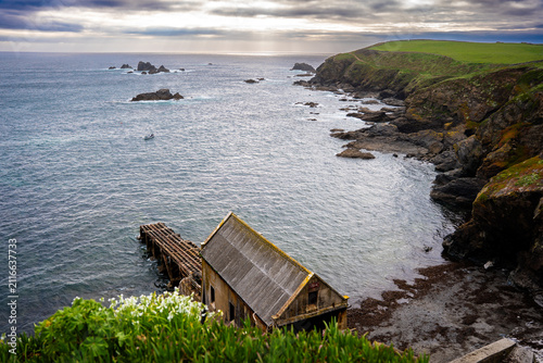 Coastal Landscape of South West England Under Moody Clouds and a small Wooden House on the Shore