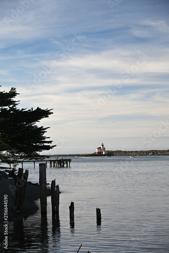 View overlooking old pilings at Coquille River Lighthouse across the bay in the distance with boats fishing and crabbing