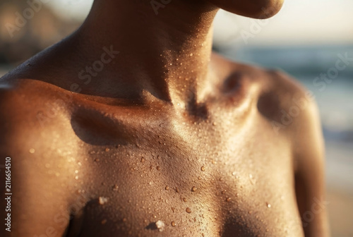 Close up of woman chest and collarbone covered in water drops outdoors at sunset