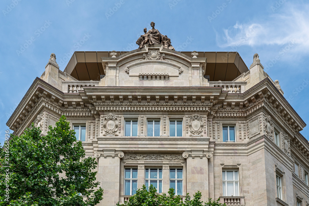 Obraz premium Upward view of the ornate neoclassical corner tower and pediment of the Hungarian National Bank building in Budapest, Hungary
