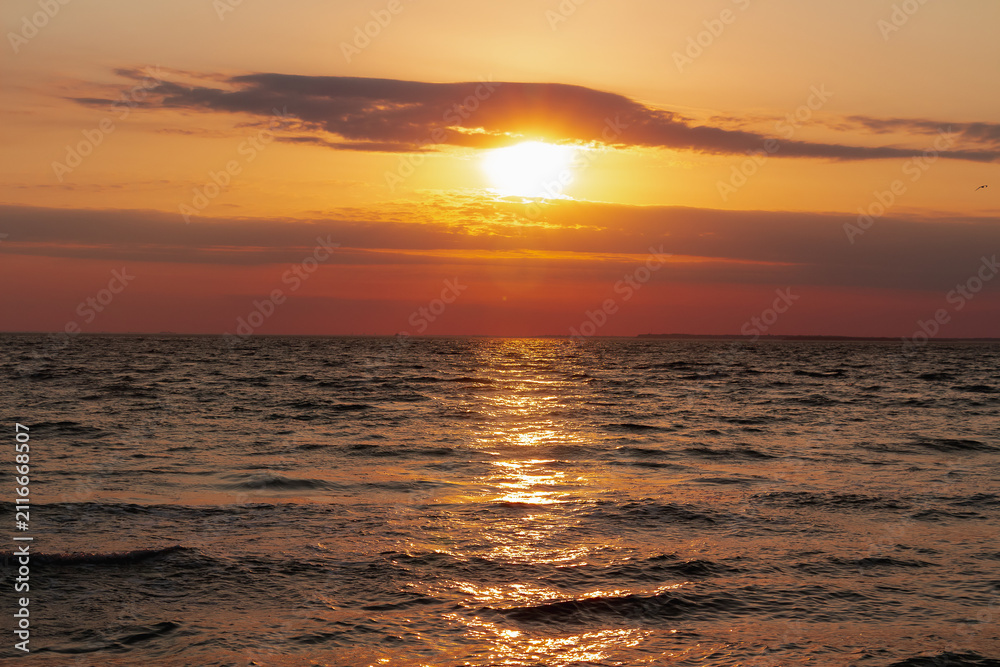 Fototapeta premium Dramatic evening sky with the sun rays crossing the clouds over Kinburn spit. Harmony of meditation near the beautiful sea waves of Normandie and Bretagne. The golden and blue hour of the sunset.