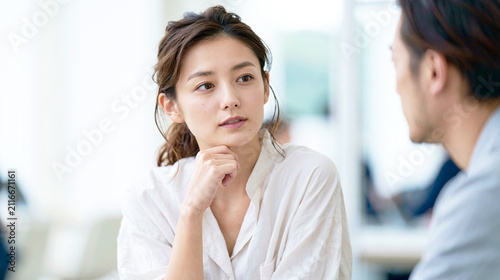 明るいオフィスで男性の話を真剣に聞く女性会社員
