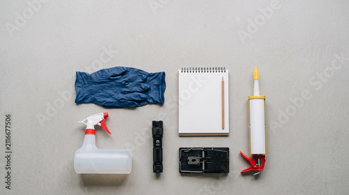 Pest control equipment including a spray bottle, mouse trap, flashlight, and protective glove.