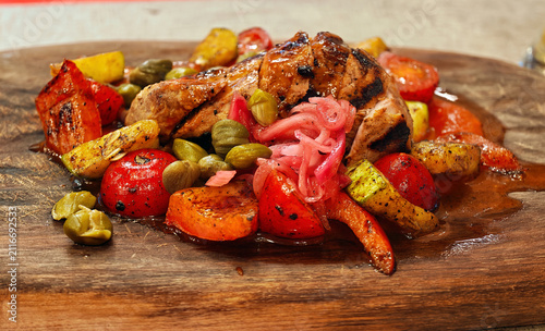 Roast pork or chicken thighs, cooked with grilled vegetables. The side dish includes cherry tomatoes, courgettes and sweet peppers.