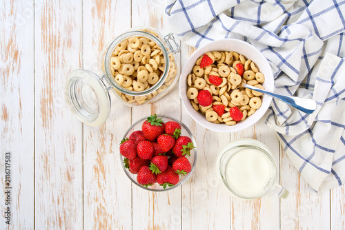 Bild auf Leinwand Quick breakfast for kids with corn hoops and strawberry on a light kitchen table, top view