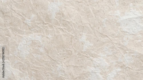High resolution close-up of natural recycled paper with a distinct crumpled texture and organic brown fiber flecks. This eco-friendly material surface is ideal for vintage design projects