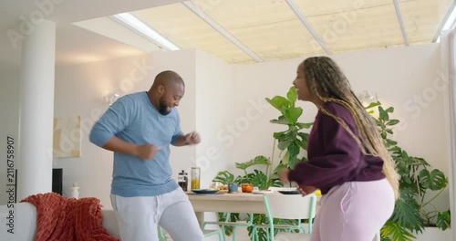 African American couple exchanging smiles and dancing, bonding near dining table with juice