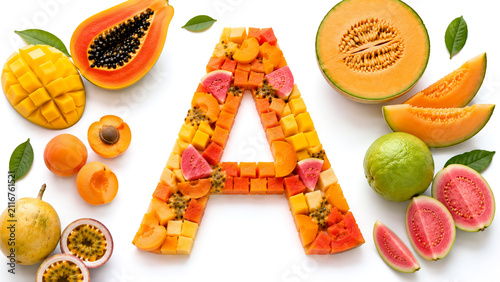 Top view of fresh fruits rich in vitamin A arranged as the letter A on a white background. Healthy nutrition concept with mango, papaya, cantaloupe, apricot, guava, and passion fruit.