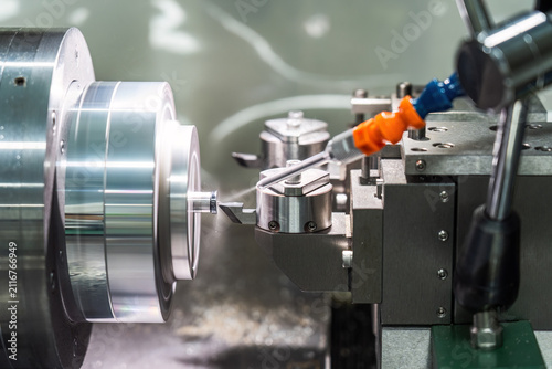 Картината върху платно A metal lathe performs precision cutting on a cylindrical workpiece, with coolant spraying during the industrial machining process