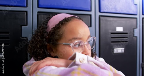 African American teen spotting motion leaning on arms turning head waiting at lockers with glasses