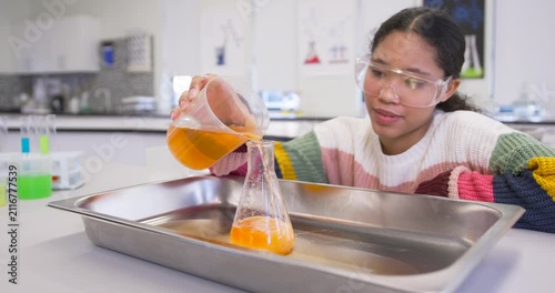 Child pouring orange from beaker into flask in lab demo, causing foam overflow, smiling, copy space