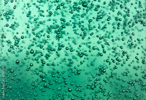 Macro texture of mint green gel with tiny air bubbles suspended for cosmetic background