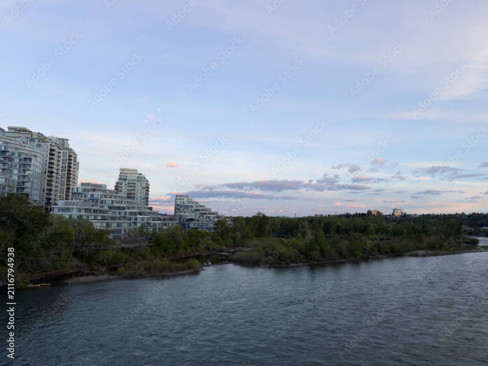 Obraz premium Bow River flowing past residential condominium buildings under a morning sky in Calgary