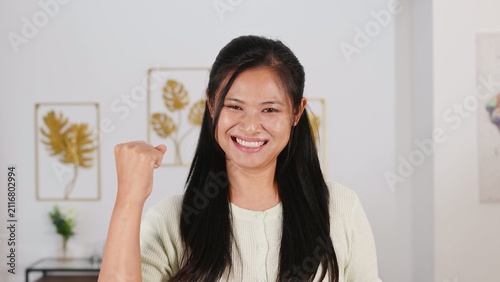 Foto Smiling Young Woman Celebrating Success with Raised Fist Gesture Indoors