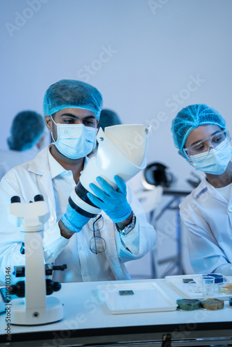 Bild auf Leinwand Engineering team inspecting prototype prosthetic limb part near microscope on ta