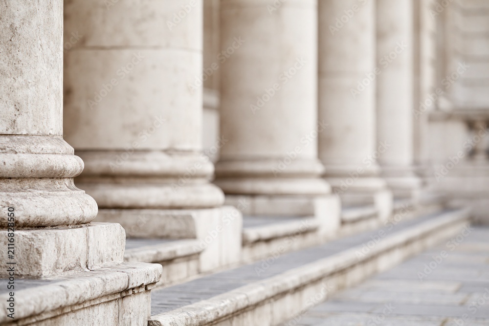 Fototapeta premium Close-up view of weathered stone columns and steps on a classical building facade showcasing architectural details