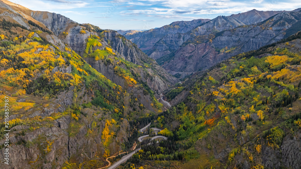 Obraz premium Aerial view of Colorado mountains canyon fall foliage trees along Million Dollar Highway and car travel on winding road during autumn season near Ouray amongst San Juan Mountains landscape