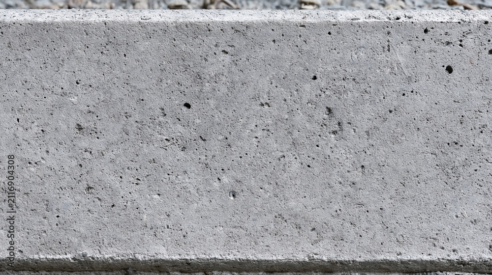 Fototapeta premium Close-up textured surface of a rough gray concrete curb, showing imperfections and granular detail