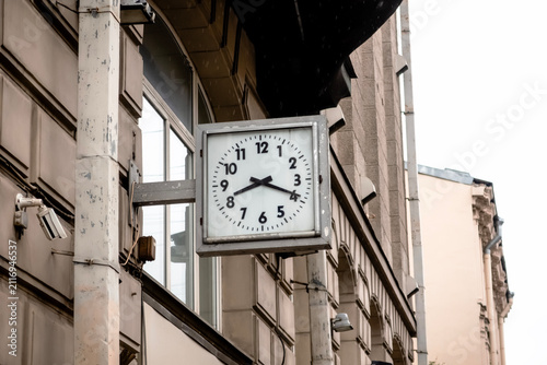 An old clock on the wall of a building showing eight hours nineteen minutes