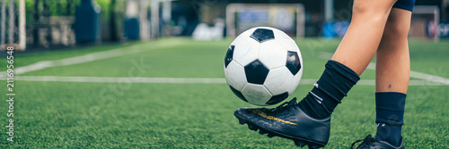 Young boy juggling soccer ball with foot at indoor field.