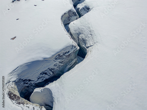 Принти на полотні Aerial close up view of a deep crevasse in a snowy glacier.