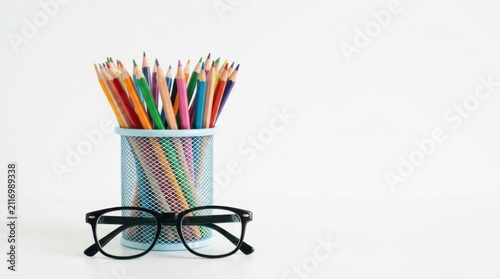 Colorful pencils in a blue metal holder with blackframed eyeglasses isolated on white background