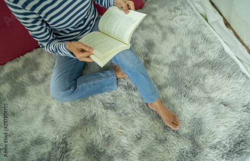 Obraz na płótnie Woman reading a book on a cozy rug at home
