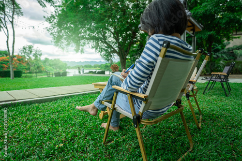Quadro su tela Woman journaling outdoors in peaceful green park surrounded by nature