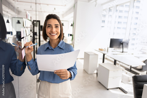 Foto Portrait of businesswoman stands in office, holding paper document, organizing p