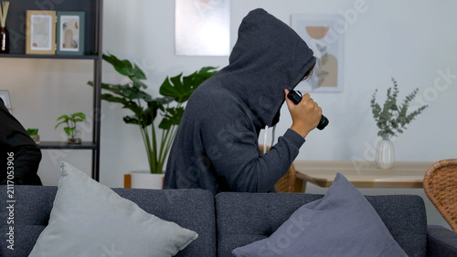 Konstfotografi Person in Dark Hoodie Holding Flashlight Sneaking Behind Sofa in Living Room