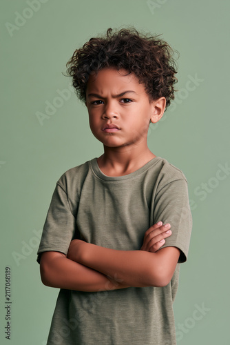 angry POC boy confused with folded arms on isolated on plain green colour studio background