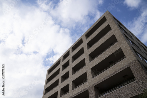 Plakat w ramie 青空と白い雲を背景にそびえ立つブラウンのタイル張りが美しいマンション外観