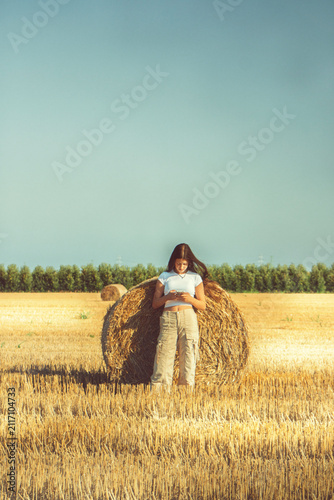 фотографія A vintage portrait of a teenage girl finds a quiet moment in a nostalgic hayfield, absorbed in her smartphone